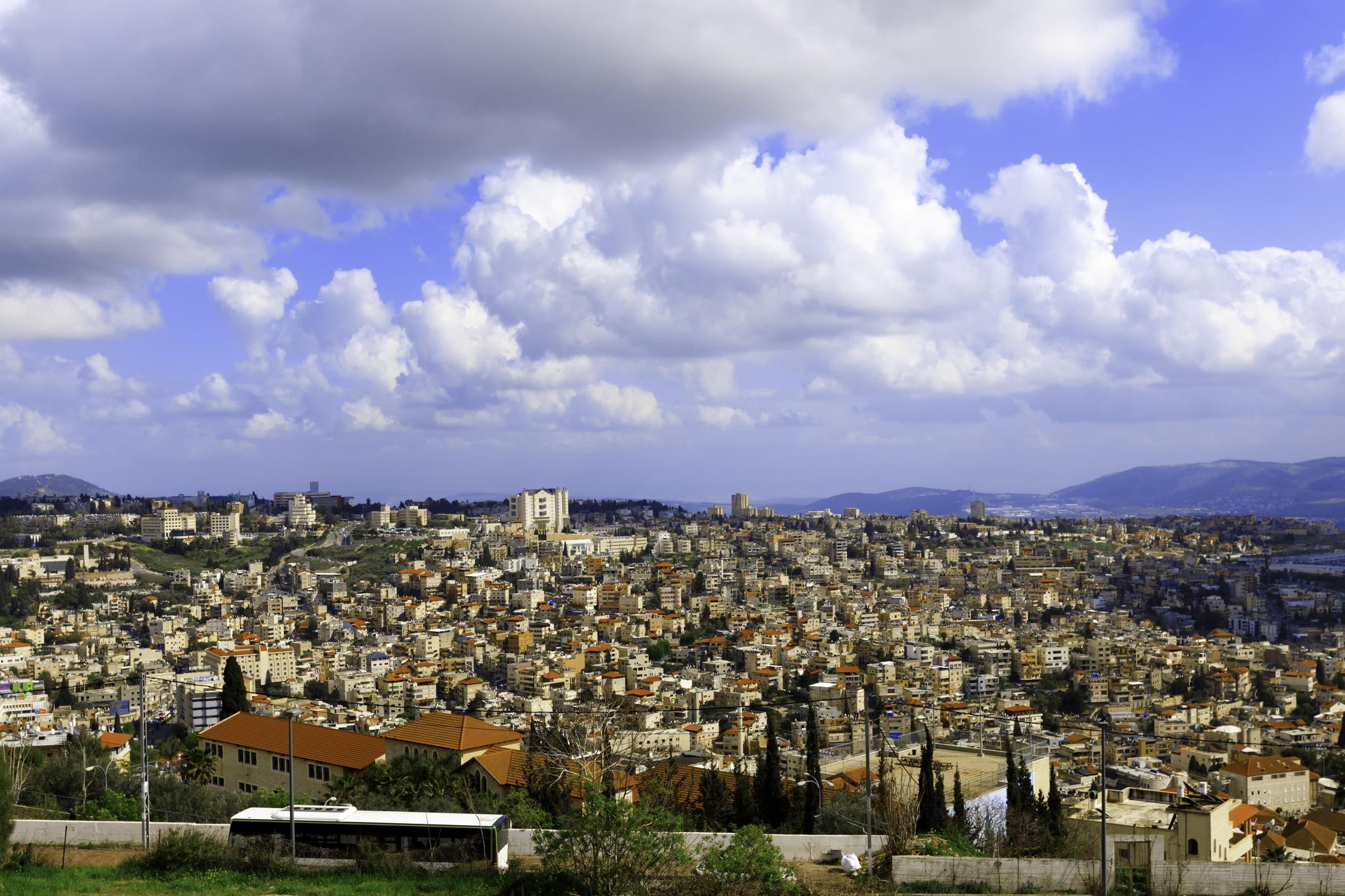 Vista panorámica de la ciudad de Nazaret extendida sobre las colinas de Galilea bajo un cielo azul con nubes blancas.
