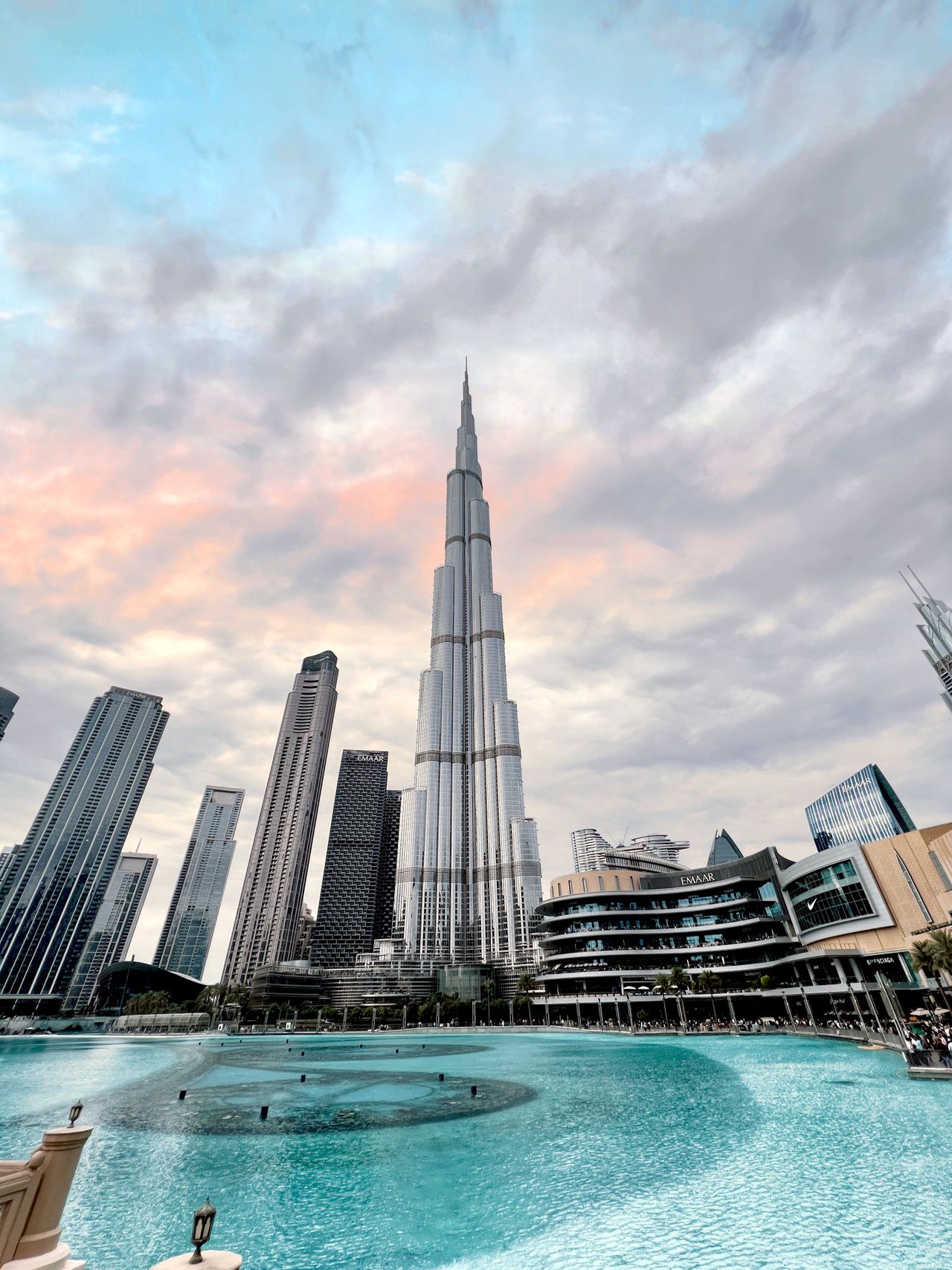 Imponente rascacielos Burj Khalifa sobre el lago de las fuentes y el centro comercial Dubai Mall al atardecer.